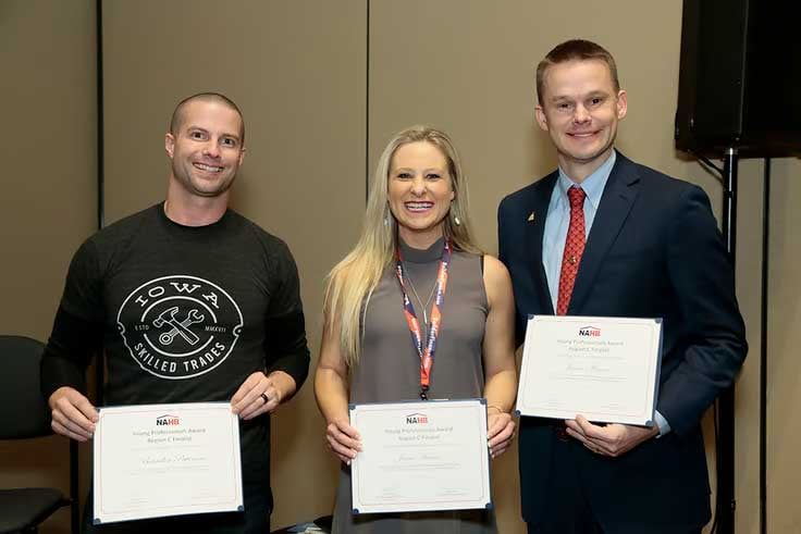 Woman, two men smiling, each holding an award